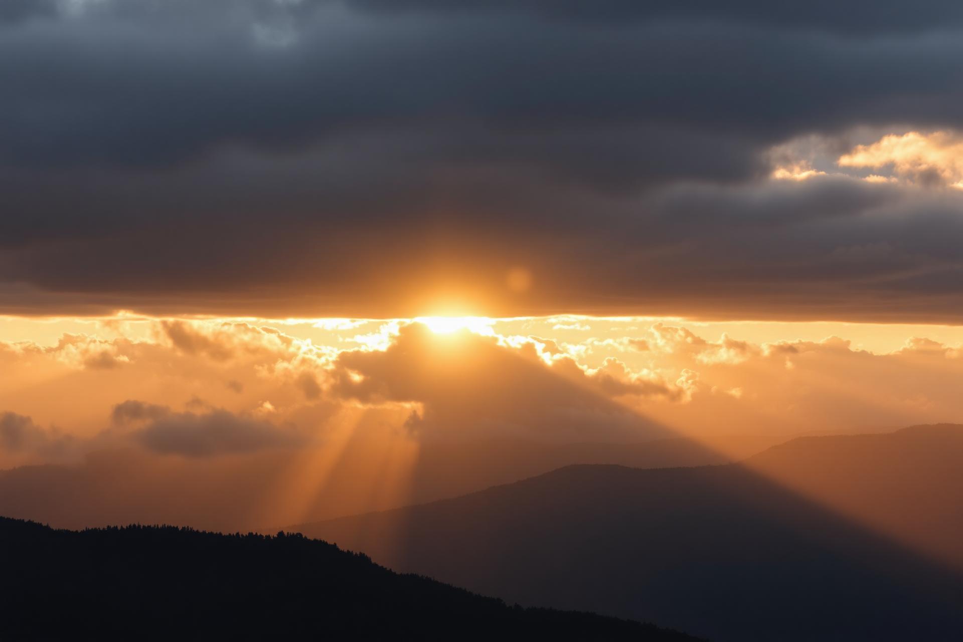 Sunrise breaking through clouds over mountains